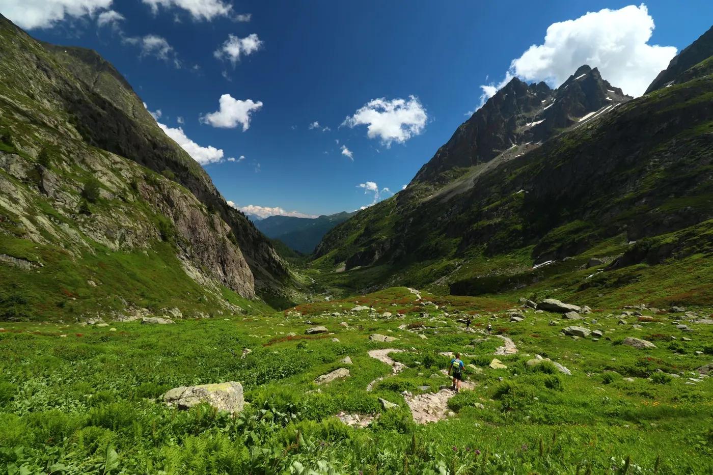 Breathtaking view of Montblanc's lush green valley with hiking trail and towering peaks.