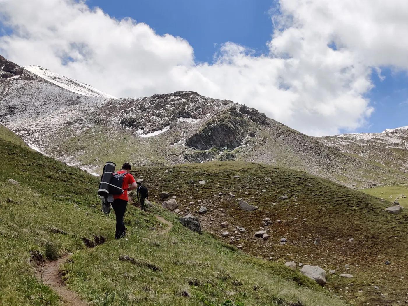 Hiker with gear trekking in Tien Shan Mountains, Almaty, Kazakhstan. Scenic views and adventure.