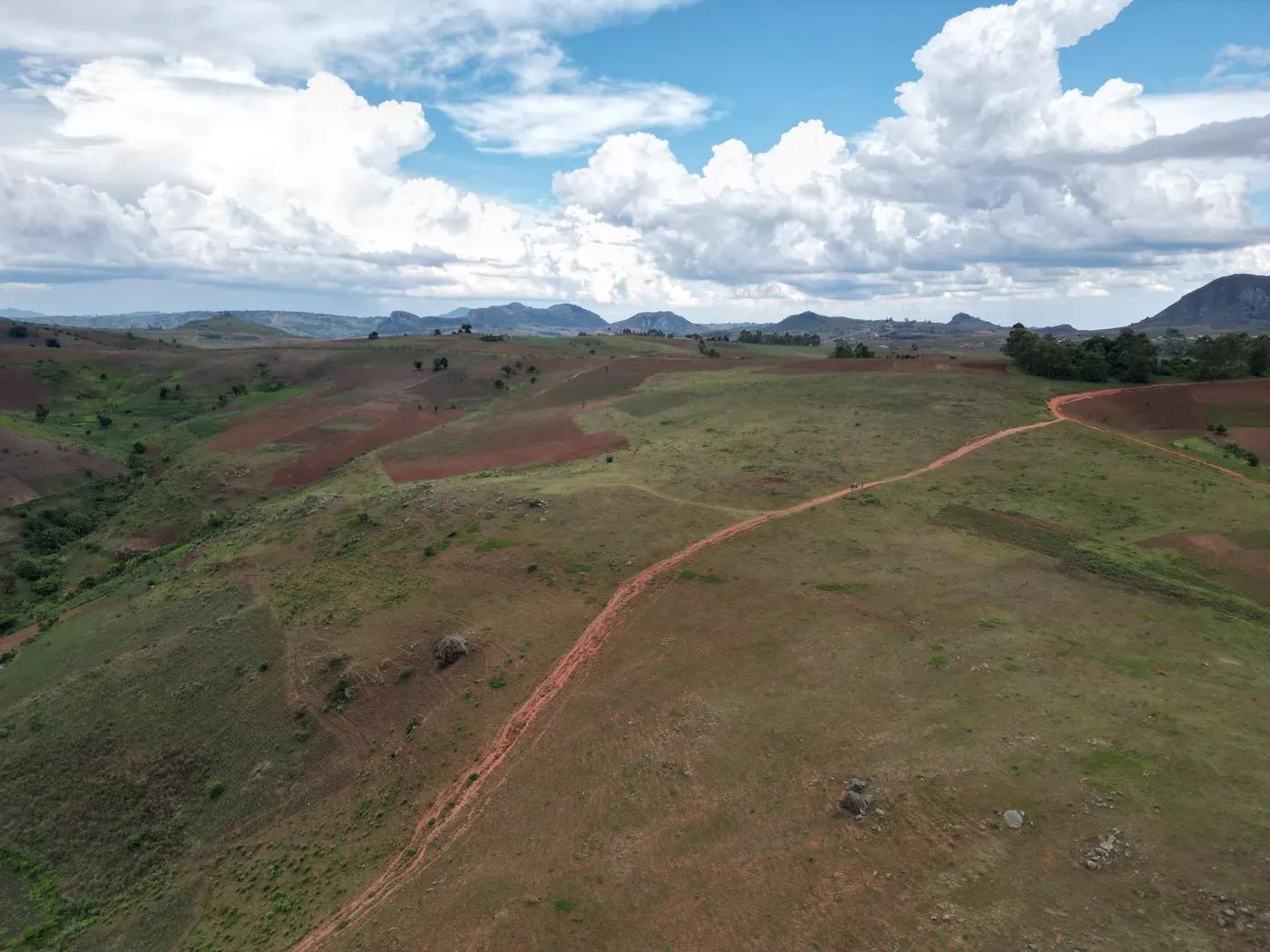 Breathtaking aerial view of Malawi's expansive green and brown highlands under a vibrant, cloud-filled sky.