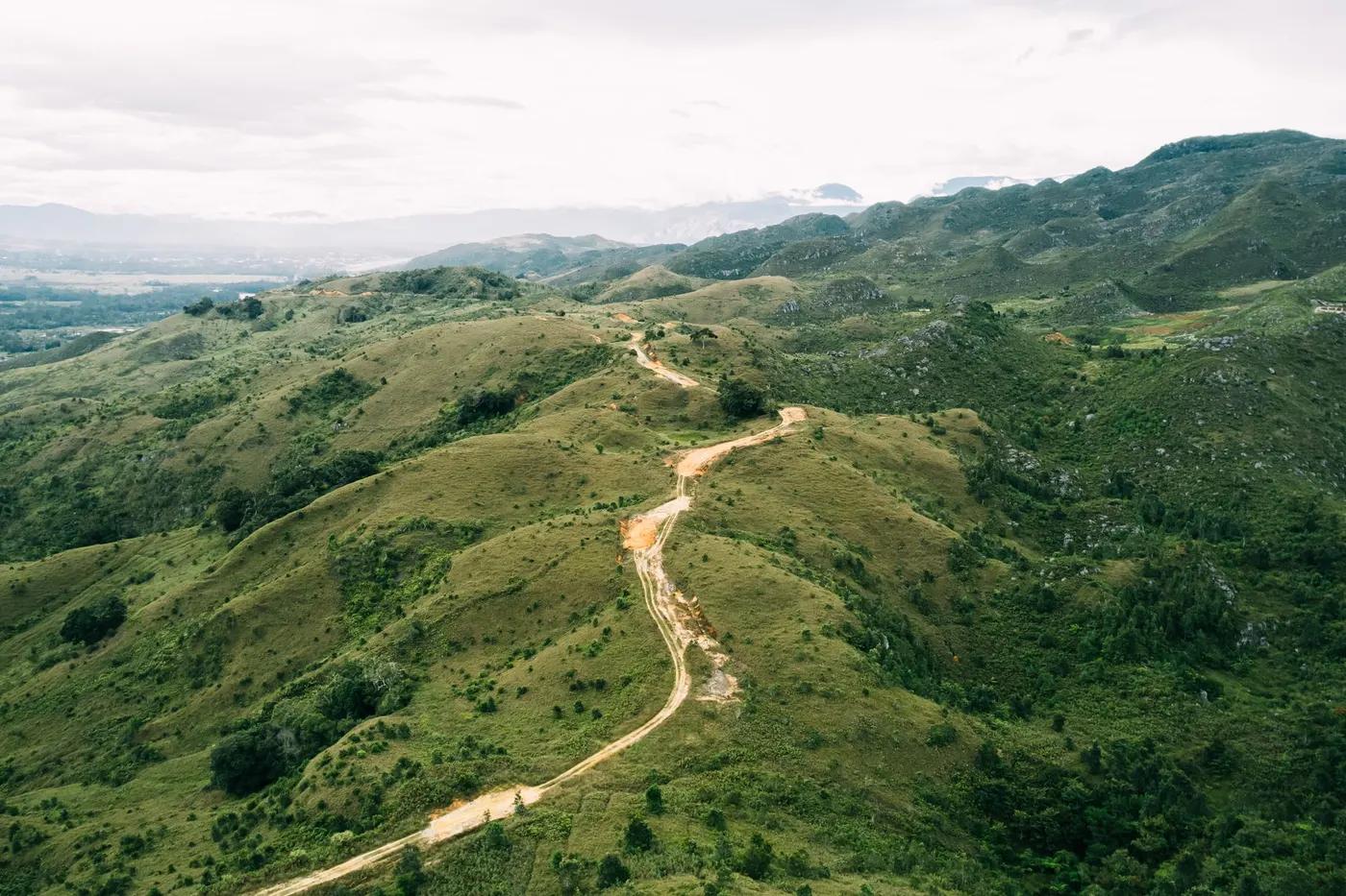 Breathtaking aerial view of a winding road through the lush green hills of Papua Pegunungan, Indonesia.