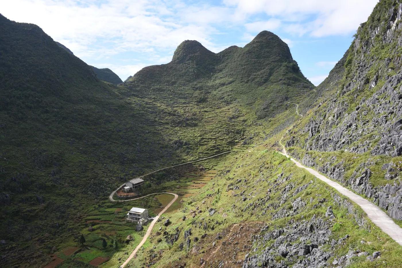 Beautiful mountain valley with greenery and a winding path under a clear blue sky.