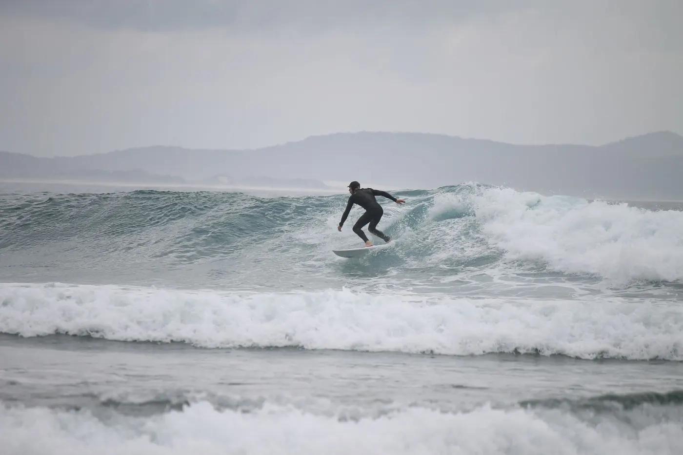 A surfer skillfully gliding on waves at Crescent Head, NSW, Australia.