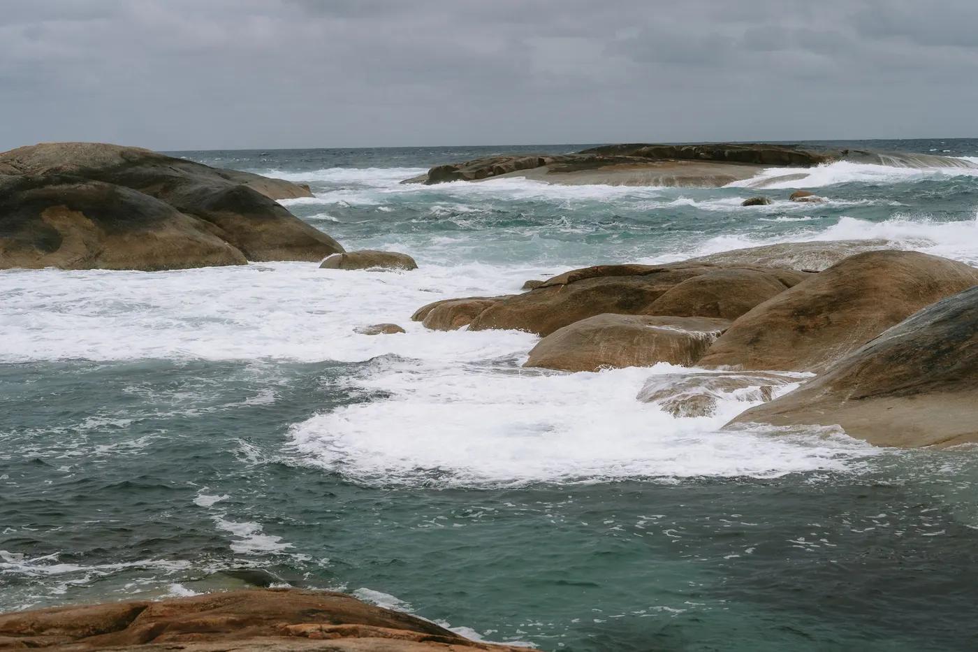Waves crash over rocks on a cloudy day at Yallingup, WA, capturing the wild beauty of the Australian coast.