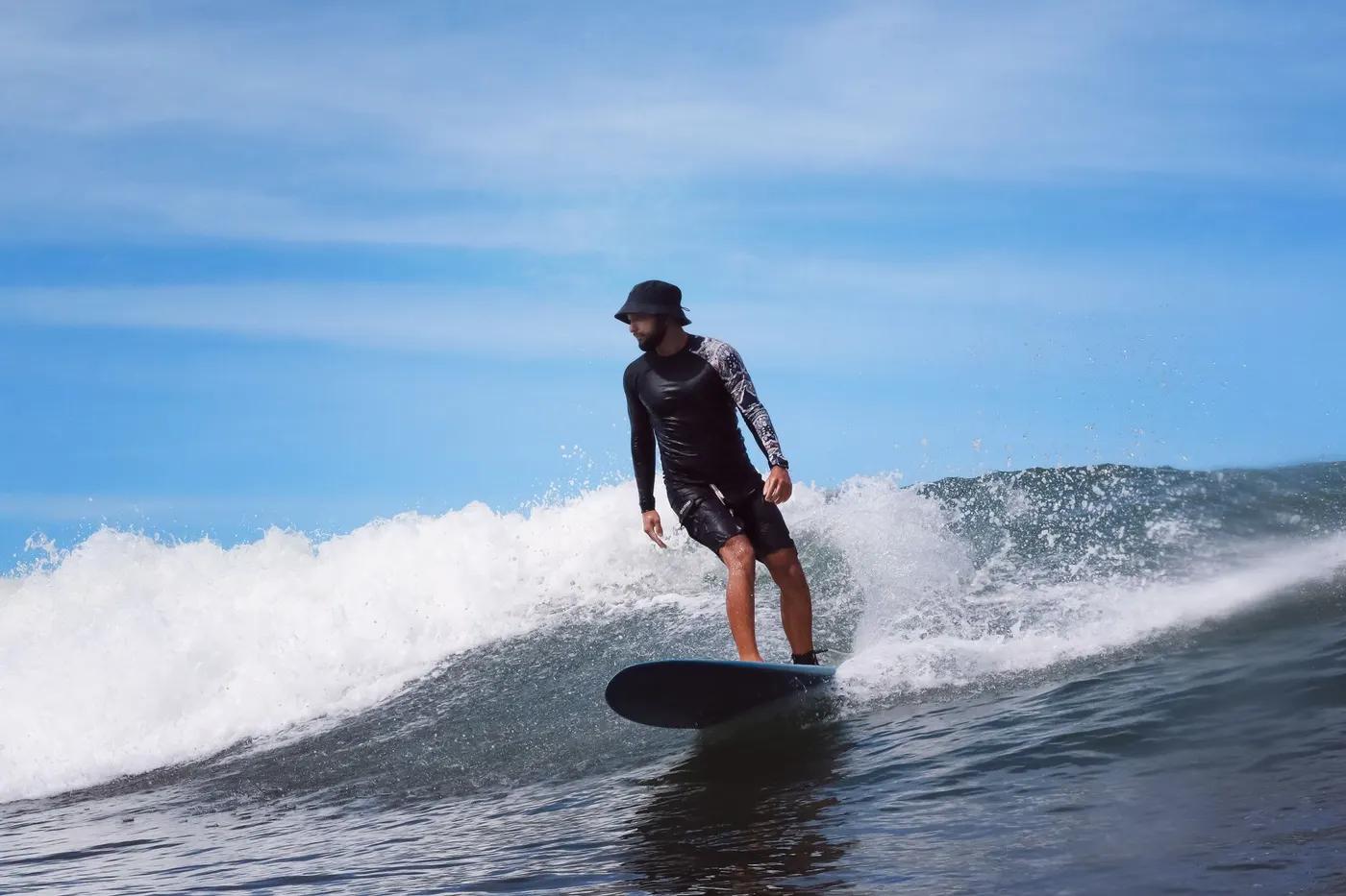 Male surfer skillfully navigating a wave on a clear sunny day, showcasing surf skills.