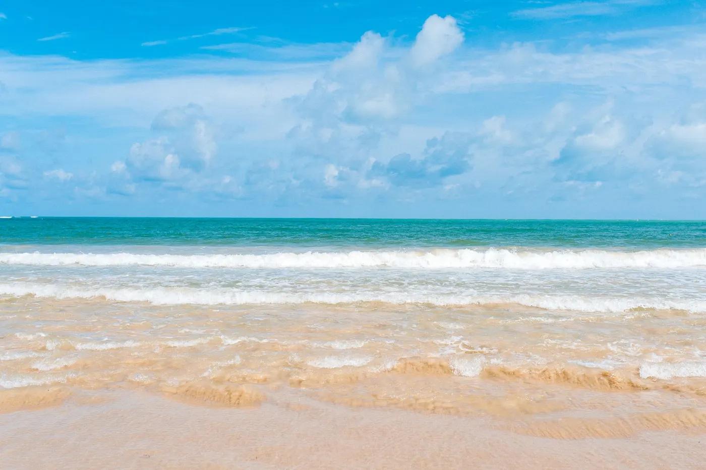 Idyllic beach scene in Phuket, Thailand with turquoise waters under a blue sky.