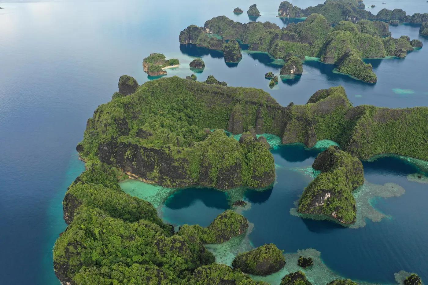Breathtaking aerial view of lush green islands in Raja Ampat, West Papua, Indonesia, showcasing pristine blue waters.