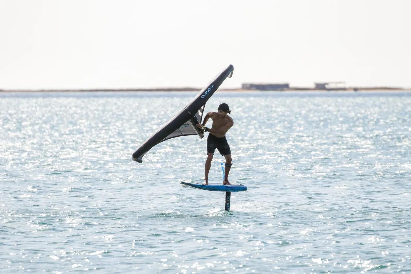 Man wing foiling on a sunny day, showcasing thrilling sea sport action.